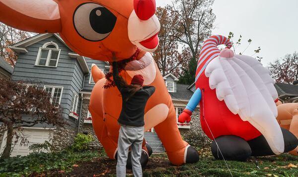 Midtown resident Wendy Cohn works to get her (very large!) inflatable Christmas decorations upright again after some windy weather.