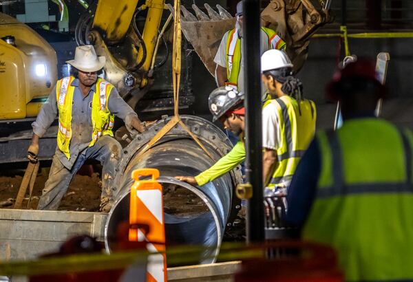 A large 30-inch pipe was seen being lowered into the hole at 11th and West Peachtree Street Tuesday morning, June 4, 2024. According to the city, the Department of Watershed Management was ready to start installing and conducting the remaining steps to restore water service. (John Spink/AJC)