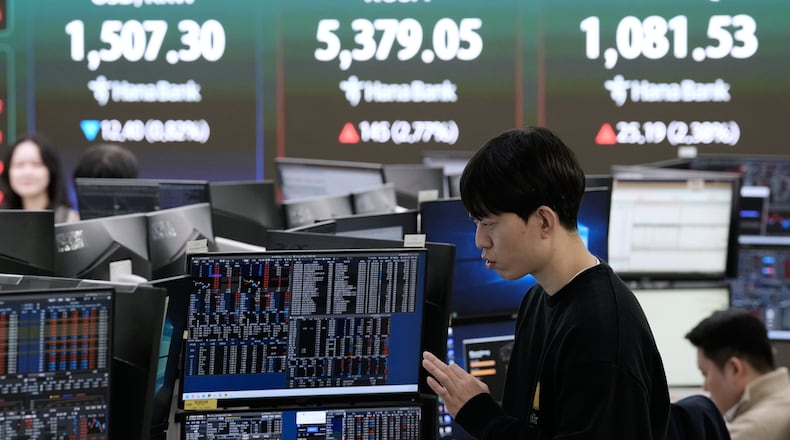 A currency trader works near a screen showing the Korea Composite Stock Price Index (KOSPI), top center, and the foreign exchange rate between U.S. dollar and South Korean won, top center left, at the foreign exchange dealing room of the Hana Bank headquarters in Seoul, South Korea, Friday, April 3, 2026. (AP Photo/Ahn Young-joon)