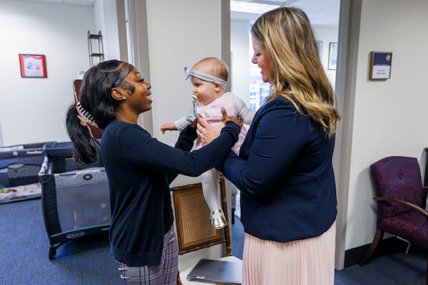Florida Rep. Fiona McFarland, R-Sarasota, right, hands 7-month-old daughter Grace Melton to Mycah Moore, a childcare worker who helps McFarland, as she leaves her office for a committee hearing, Thursday, April 17, 2025, in Tallahassee, Fla. (AP Photo/Colin Hackley)
