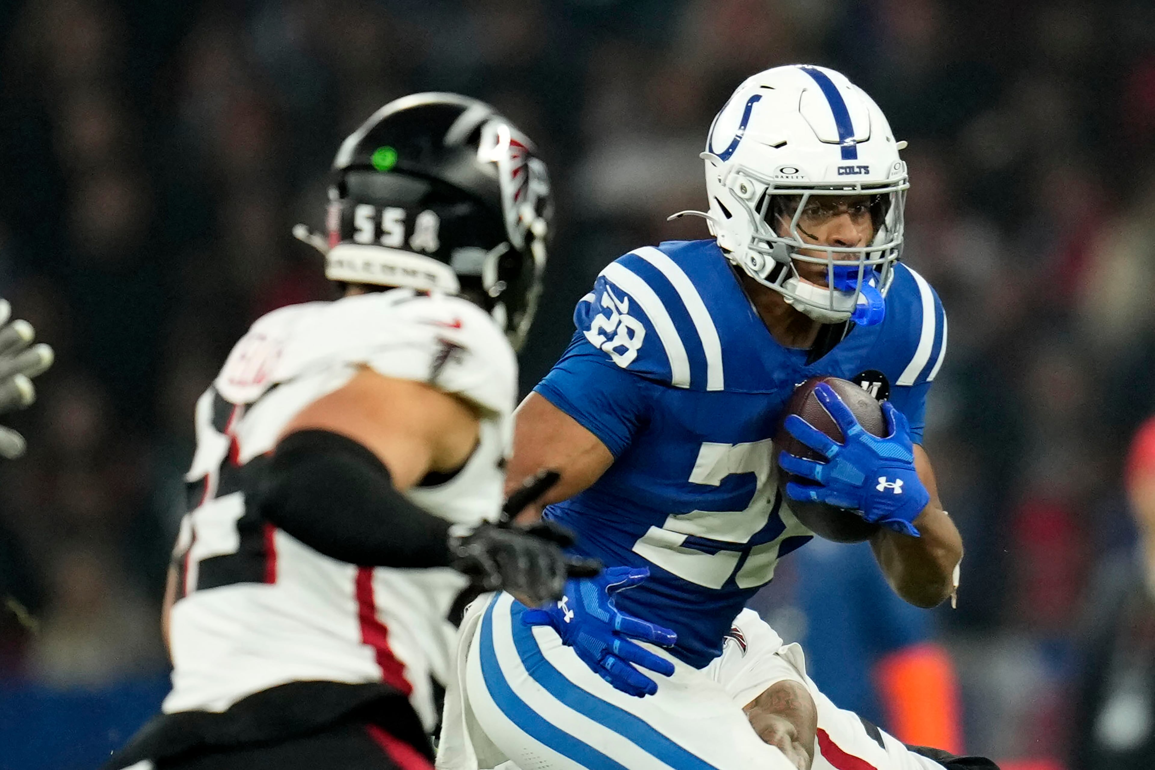 Indianapolis Colts running back Jonathan Taylor (28) runs from Atlanta Falcons linebacker Kaden Elliss (55) during the first half of an NFL football game, Sunday, Nov. 9, 2025, in Berlin, Germany. (AP Photo/Ebrahim Noorozi)
