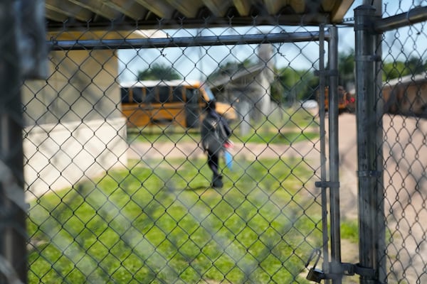A person walks inside a barbed wire fence inside Ferriday High School in Ferriday, La., Thursday, May 22, 2025. (AP Photo/Gerald Herbert)