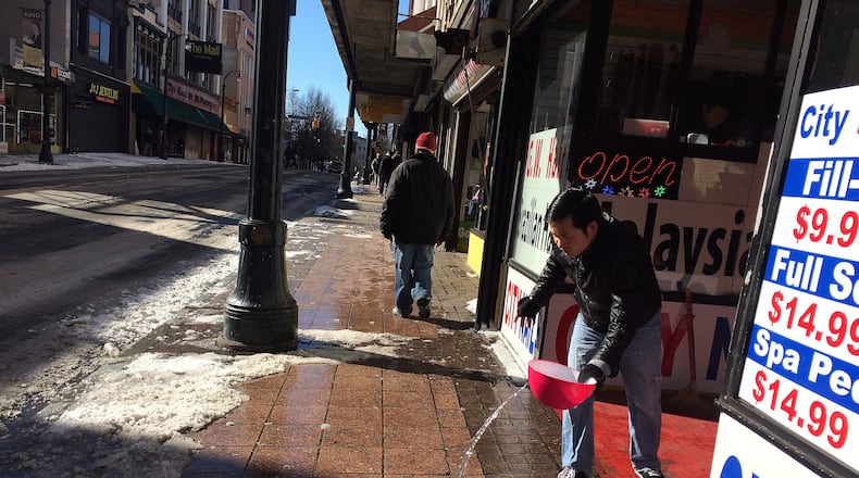 January 30, 2014 Atlanta: Dwayne Ngo uses water to help clear the ice off the sidewalk in front of the City Nails salon in Downtown Atlanta on Thursday morning January 30, 2014. Ngo said he wasn't expecting any customers to come by until it warmed up in the afternoon. BEN GRAY / BGRAY@AJC.COM