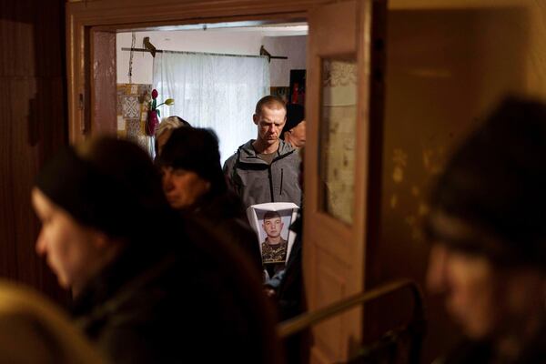 A man holds a photograph of Dmytro Shapovalov, a Ukrainian serviceman, during his funeral ceremony in Yosypivka village, Vinnytsia region, Ukraine, on Friday, June 13, 2025. (AP Photo/Evgeniy Maloletka)