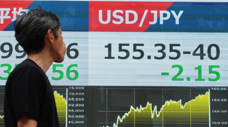 A person walks past an electronic board showing the U.S. dollar and Japanese yen exchange rate at a securities firm in Tokyo on Monday, Aug. 3, 2026. (AP Photo/Eugene Hoshiko)