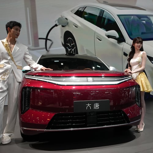 FILE - Models stand next to a latest EV car from Chinese automaker BYD showcased at the Auto China 2026, in Beijing, April 25, 2026. (AP Photo/Andy Wong, File)