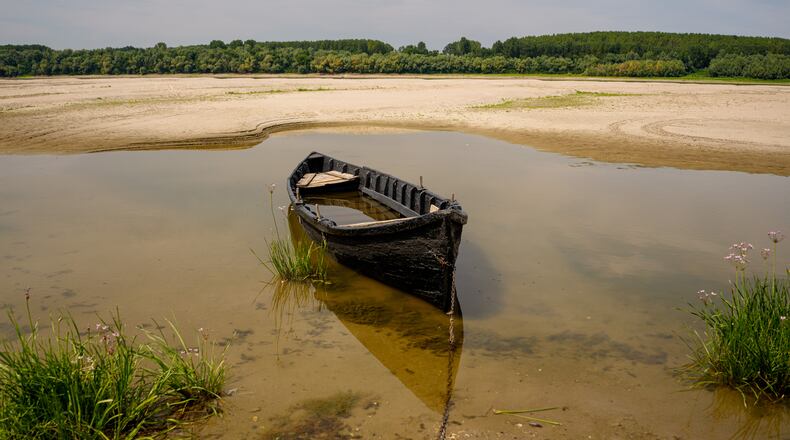 A boat is banked on the sand in an area usually submerged in water along the Danube River during low water levels in Rasova, Romania, Monday, Aug. 3 2026. (AP Photo/Andreea Alexandru)