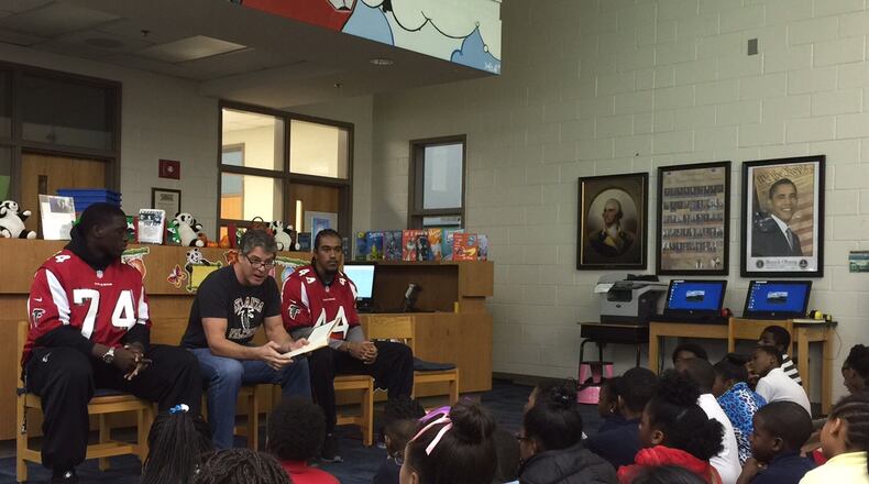 Former Atlanta Falcons defensive end Tim Green, center, flanked by current players Joey Mbu, left, and Vic Beasley Jr., reads to students at Parkside Elementary in Atlanta. MARLON A. WALKER/marlon.walker@ajc.com
