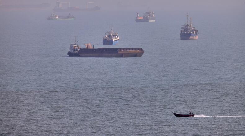 FILE - A small boat sails past cargo ships and other commercial vessels anchored in the Strait of Hormuz off Bandar Abbas, Iran, Wednesday, Aug. 5, 2026. (Amirhosein Khorgooi/ISNA via AP, File)