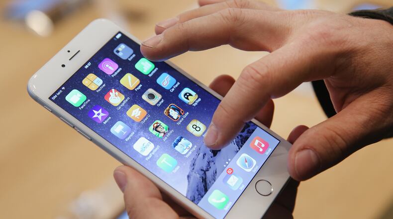 BERLIN, GERMANY - SEPTEMBER 19: A shopper ltries out the new Apple iPhone 6 at the Apple Store on the first day of sales of the new phone in Germany on September 19, 2014 in Berlin, Germany. Hundreds of people had waited in a line that went around the block through the night in order to be among the first people to buy the new smartphone, which comes in two versions: the Apple iPhone 6 and the somewhat larger Apple iPhone 6 Plus. (Photo by Sean Gallup/Getty Images)