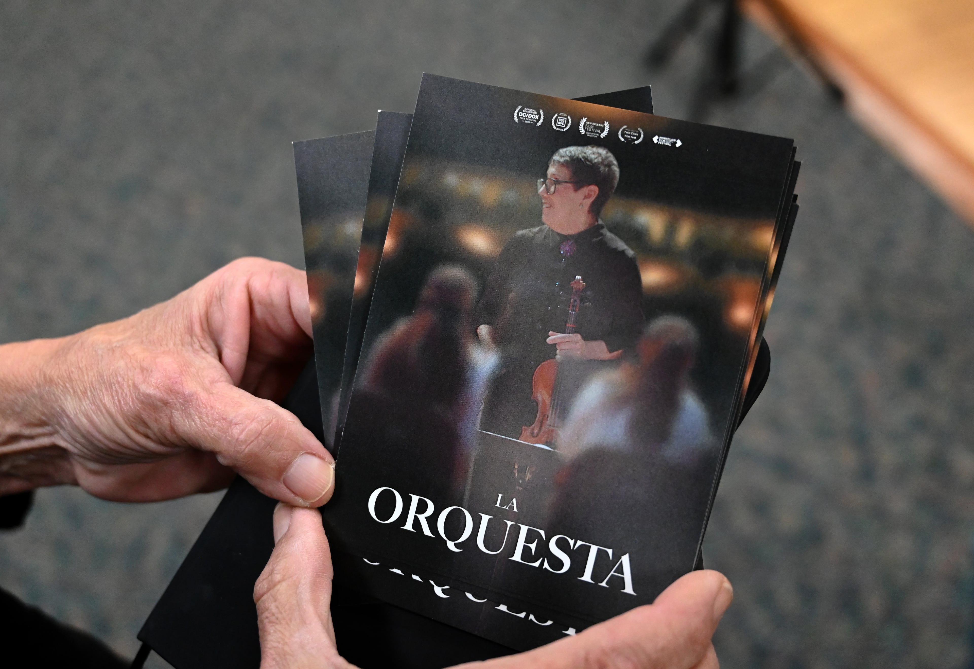 Music teacher Juana Alzaga holds promotional printouts for the film “La Orquesta," which was the result of a documentary crew embedding with the orchestra in 2024. The doc debuts Nov. 25 on PBS and its streaming platforms. (Hyosub Shin/AJC)