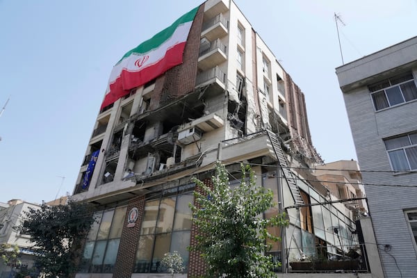 An Iranian flag hangs on a building which was hit by an Israeli strike last week, in Tehran, Iran, Wednesday, June 25, 2025. (AP Photo/Vahid Salemi)