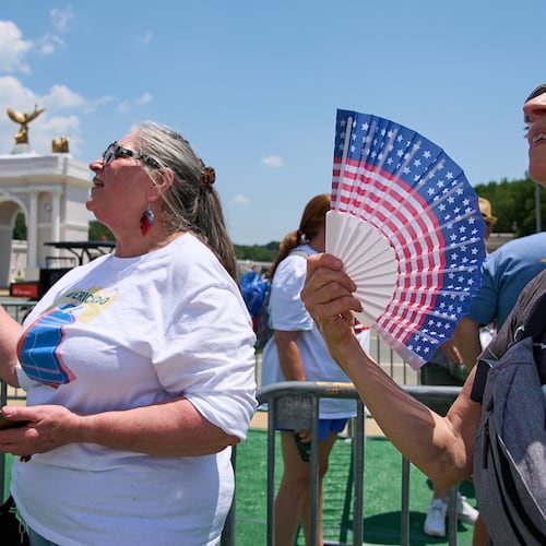 FILE - Mickelina Papotto, of Salem, Ore., left, and Lorie Odegaard, of Gaithersburg, Md., fan themselves while waiting in line for the ferris wheel at the Great American State Fair on the National Mall, July 1, 2026, in Washington. (AP Photo/Jacquelyn Martin)