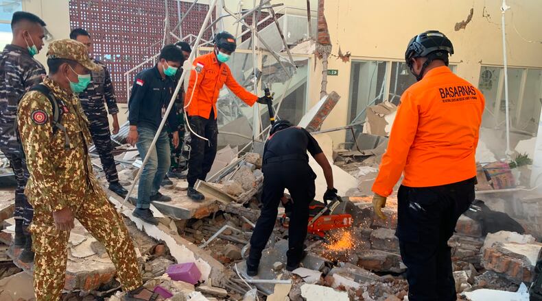 In this photo released by the Indonesian National Search and Rescue Agency (BASARNAS), rescuers attempt to clear debris at building damaged by an earthquake in Maumere, East Nusa Tenggara Province, Indonesia, Saturday, Aug. 15, 2026. (BASARNAS via AP)