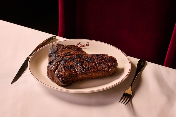 A steak on a plate on a white tablecloth with fork and knife