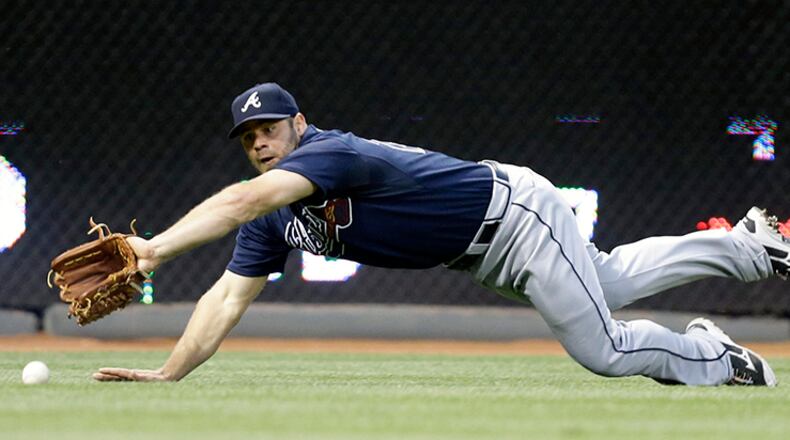 Evan Gattis, making a start in left field, misses a double hit by Cincinnati Reds' Brandon Phillips to drive in a run in the fourth inning.
