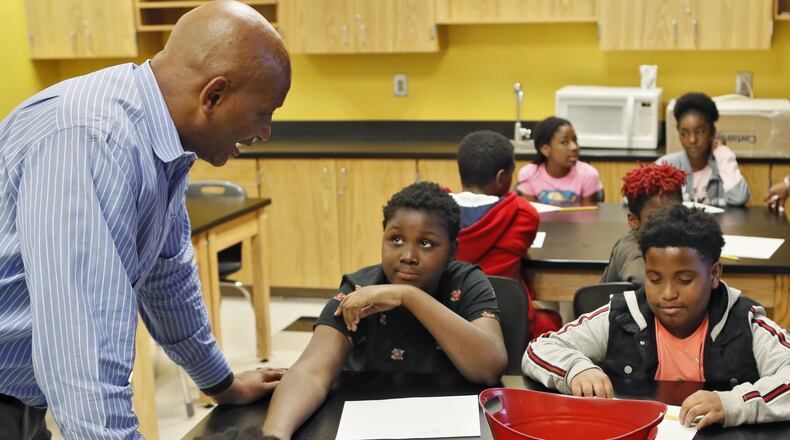 Principal Artesza Portee (left) checks on Alex Stilwell (right) and Cedric Shy, both 11, as they write what things they are nervous about starting middle school. When complete, the class discusses them anonymously. Incoming sixth-graders at Sylvan Hills Middle School take part in the summer bridge program designed to help students leaving elementary school adjust to their new life as middle schoolers. BOB ANDRES / ROBERT.ANDRES@AJC.COM