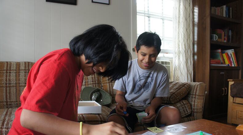 Javy (left) and Teo McGinnis, 12-year-old twin sons of El Refugio volunteer Marilyn McGinnis, play Monopoly in the living room at El Refugio. CONTRIBUTED BY STELL SIMONTON
