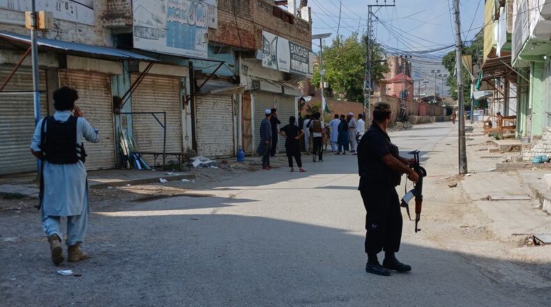 In this photo taken with a smartphone, police officers secure a road leading to the site of a powerful bomb at a mosque in Kohat, Pakistan, Friday, Sept. 18, 2026. (AP Photo/B.S. Gillani)