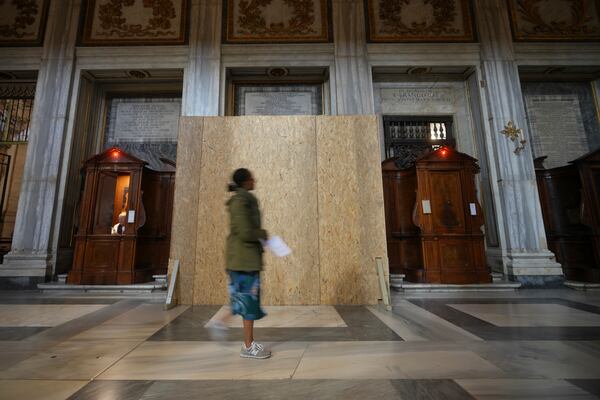 A woman walks past a wooden board where work in progress is taking place on the spot where Pope Francis will be buried, inside St. Mary Major basilica, in Rome, Tuesday, April 22, 2025. (AP Photo/Alessandra Tarantino)