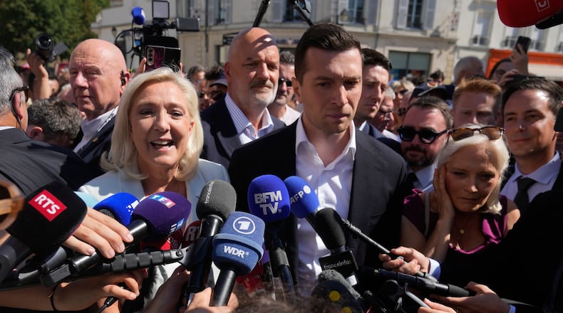 Far-right leader Marine Le Pen and Far-right party National Rally president Jordan Bardella answer journalists as they arrive to visit a market in La Fleche, western France Wednesday, July. 8, 2026. (AP Photo/Michel Euler)