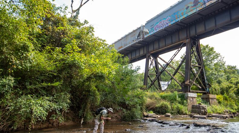 Professional Archeologist Casey Sharp, looks for quartz, soap stone or flint that shows evidence of Native American activity in the South River, an area adjacent to the highly contested Atlanta Public Safety Training Center being built on Friday, Sept 1, 2023.   (Jenni Girtman for The Atlanta Journal-Constitution)
