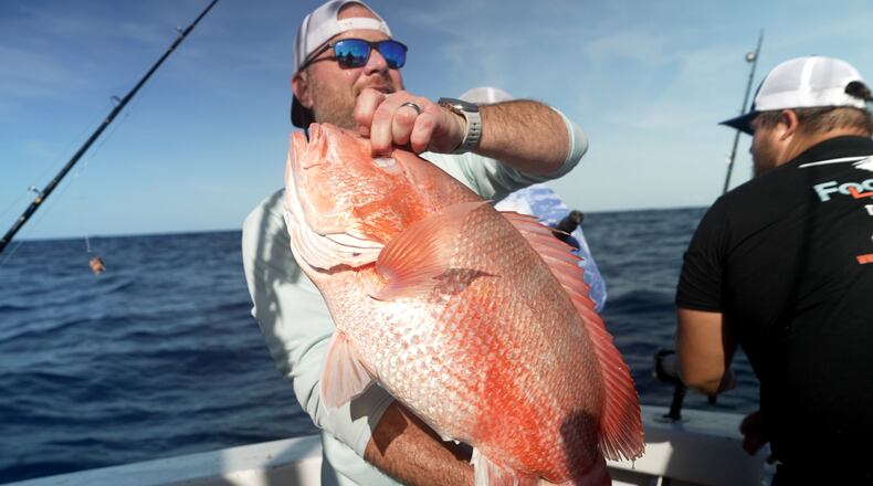 Chris Kemp holds up a red snapper he caught on the charter boat Jodie Lynn II, before releasing it back into the water miles off the coast of St. Augustine, Fla., on May 22, 2026. (AP Photo/Shelby Lum)