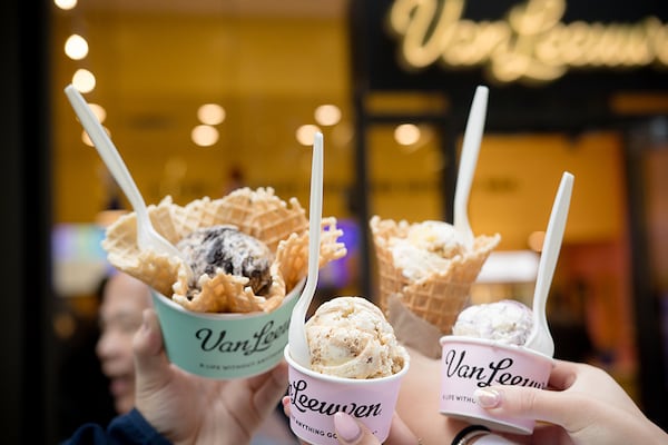Four hands hold up ice cream cups and a cone, with the cups labeled Van Leeuwen.