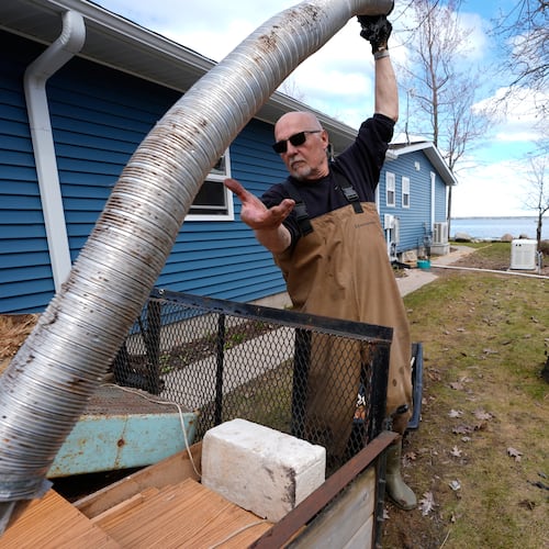 Tom Peterman cleans up outside his home from recent floods at Black Lake on Wednesday, April 29, 2026, in Grant Township, Mich. (AP Photo/Paul Sancya)