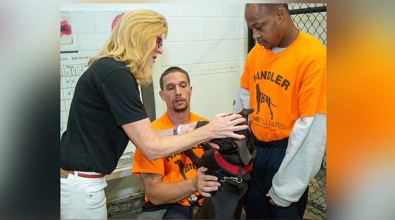 (left to right) Susan Jacobs-Meadows takes a look at Omega with handlers Jeff M & Desmon C at the Fulton County Jail as part of Canine Cellmates founded by Jacobs-Meadows 6.5 years ago. The program pairs dogs from Fulton County Animal Services that live & train with inmates at the Jail annex in Atlanta. The dogs go through a series of temperament tests to make sure that are a good fit for the program. Currently 11 inmates are training 6 dogs working on skills they will display during their graduation ceremony. Four of the six dogs have already been adopted & those adoptive parents get the opportunity to attend graduation to meet the inmates that trained their dog. (Photo by Phil Skinner)