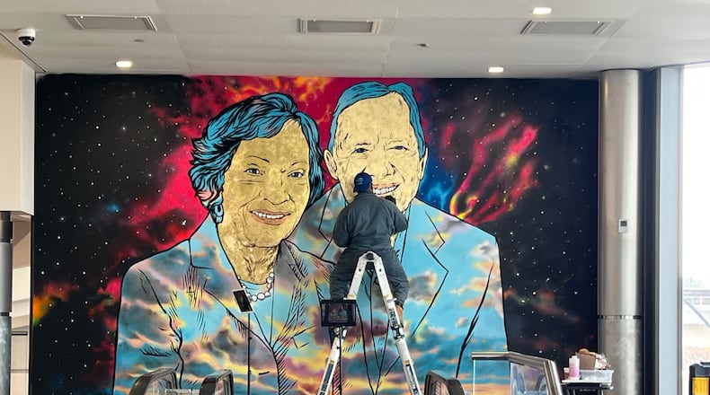 Artist Fabian Williams completes a mural of Jimmy and Rosalynn Carter at Hartsfield-Jackson Atlanta International Airport. (Kelly Yamanouchi/AJC)