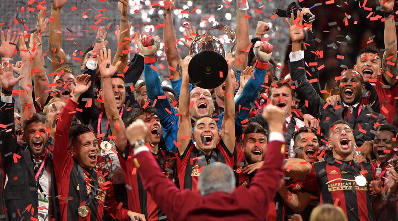 Atlanta United midfielder Miguel Almiron (center) raises the MLS Cup as they celebrate after their 2-0 win over the Portland Timbers during the 2018 MLS Cup at Mercedes-Benz Stadium on Saturday, December 8, 2018. HYOSUB SHIN / HSHIN@AJC.COM