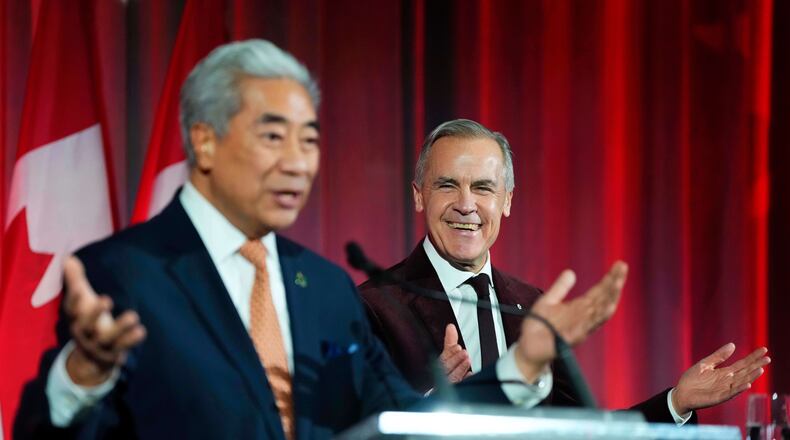 Prime Minister Mark Carney reacts as Michael Ma, Member of Parliament for Markham-Unionville, who crossed the floor from the Conservatives to the Liberals hours earlier, makes brief remarks at the Liberal caucus holiday party in Ottawa, on Thursday, Dec. 11, 2025. (Justin Tang/The Canadian Press via AP)