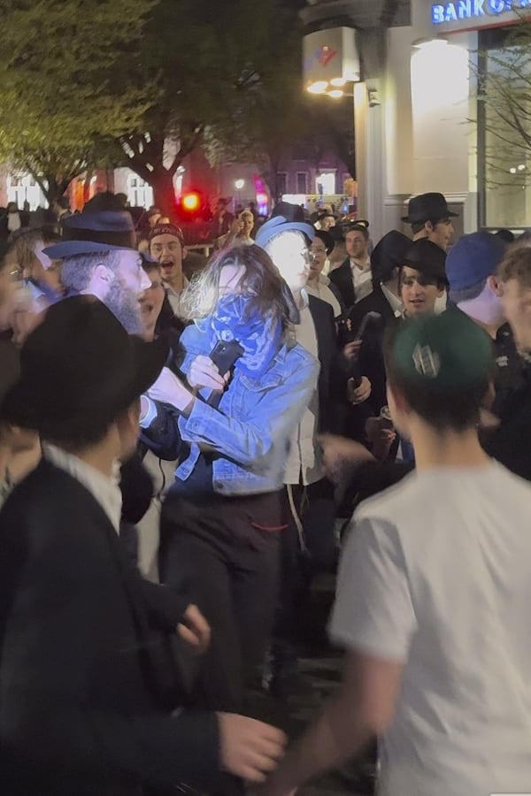 This image taken from video shows a woman and a police officer as they are pursued by a crowd of men in the Crown Heights section of Brooklyn, N.Y., on Thursday, April 24, 2025. (AP Photo)