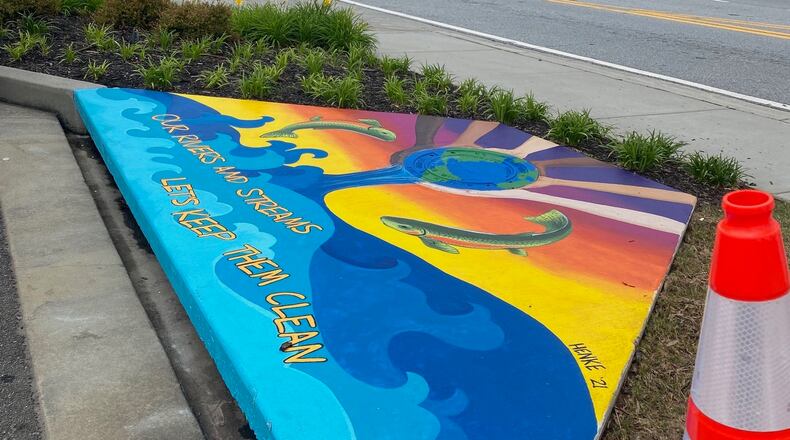 The first of two storm drain paintings in Duluth, by artist Amanda Henke, is designed to emphasize how stormwater flows directly into nearby rivers and streams and encourages citizens to avoid dumping waste into the drains. (Photo by Karen Huppertz for the AJC)