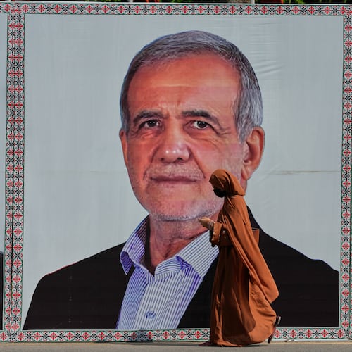 A woman walks past a welcoming billboard featuring Iranian President Masoud Pezeshkian along a roadside in Islamabad, Pakistan, Tuesday, June 23, 2026. (AP Photo/Anjum Naveed)