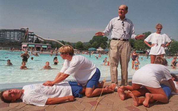FILE - Dr. Henry J. Heimlich uses lifegaurds at Coney Island swimming pool in suburban Cincinnati on Friday, July 9, 1999, to demonstrate how the Heimlich maneuver can help save people from drowning. (AP Photo/Tony Tribble, File)