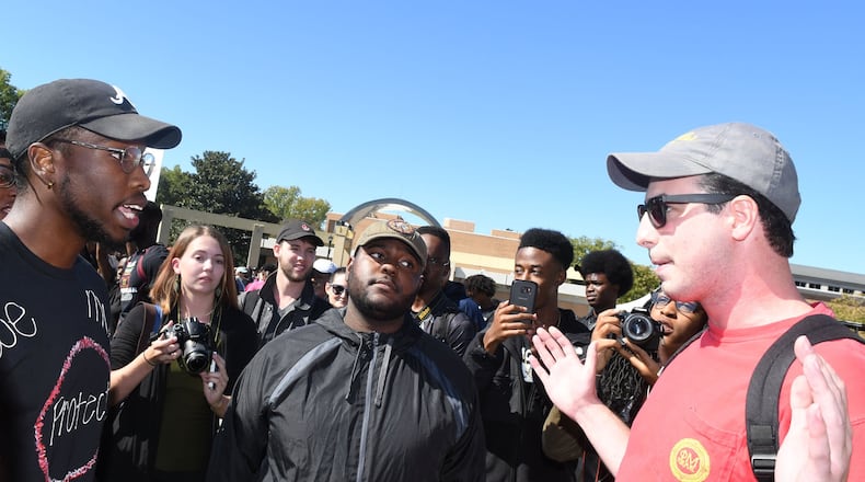 Kyrefe Harper, a senior at KSU (left) majoring in accouting, and Tahir Upshaw, a junior, (center) majoring in mechanical engineering, speak with counter-protester Neil Wolin, a junior (right) majoring in professional sales, at KSU on October 19, 2017. A group of Kennesaw State University students are protesting in support of the KSU cheerleaders who want to take a knee in protest of police brutality during the national anthem. Rebecca Breyer