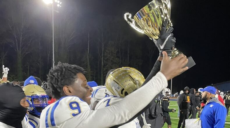 McEachern players celebrate with the championship trophy after defeated Pebblebrook 33-20 to win the Region 2-7A title on Nov. 5, 2021