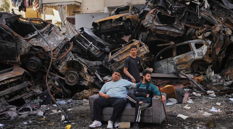 Residents sit on a sofa in front of charred cars at the site of a building destroyed in an Israeli airstrike last Wednesday in central Beirut, Lebanon, Tuesday, April 14, 2026. (AP Photo/Hassan Ammar)