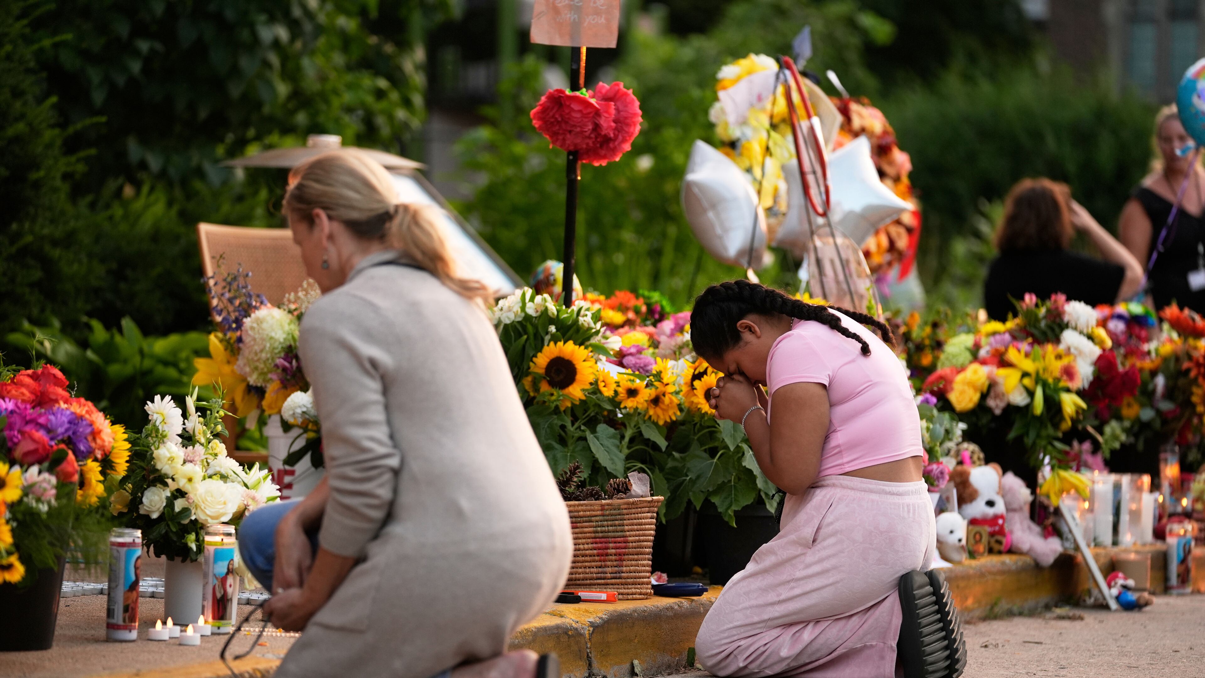 People pray at a memorial at Annunciation Catholic Church after Wednesday's school shooting, Thursday, Aug. 28, 2025, in Minneapolis. (AP Photo/Abbie Parr)