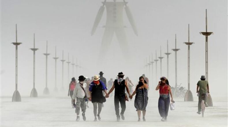 Burning Man participants walk through dust at the annual Burning Man event on the Black Rock Desert of Gerlach, Nev., on Friday, Aug. 29, 2014. Organizers call Burning Man the largest outdoor arts festival in North America, with its drum circles, decorated art cars, guerrilla theatrics and colorful theme camps. (AP Photo/The Reno Gazette-Journal, Andy Barron)