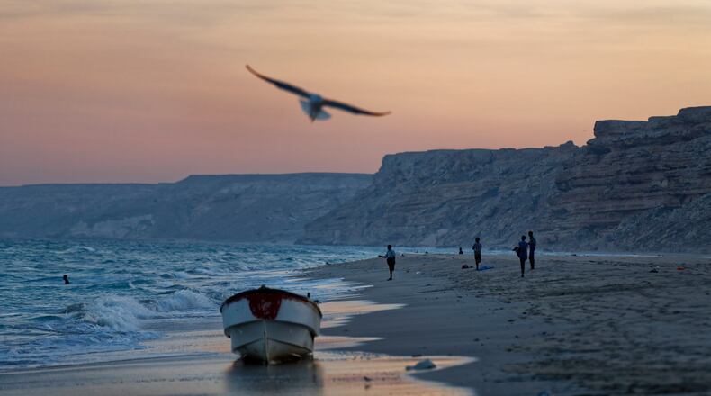 FILE - Fishermen stand on the Indian Ocean beach at dusk in the former pirate village of Eyl, in Somalia's semiautonomous northeastern state of Puntland, Somalia, Monday March 6, 2017. (AP Photo/Ben Curtis, File)