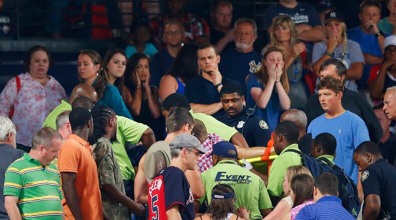 Rescue workers carry an injured fan from the stands at Turner Field during a game between Atlanta Braves and New York Yankees Saturday. The fan fell from the upper desk onto concrete and has died. (AP Photo/John Bazemore)