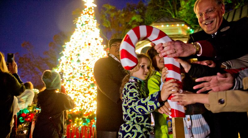 Cecily Sullivan (center) pushes the candy cane to turn on the lights on the main Christmas tree inside Six Flags Over Georgia in Austell on Friday, Nov. 21, 2014. Holiday in the Park runs through Jan.4, 2015. JONATHAN PHILLIPS / SPECIAL