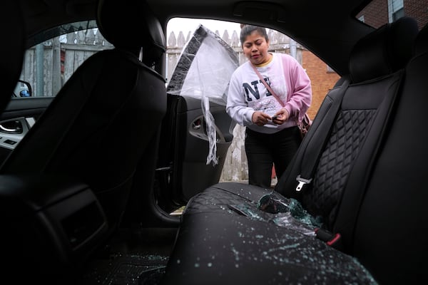 Marilu Domingo Ortiz, whose husband was taken into custody by ICE agents after they smashed a window of their family car, looks at broken glass and damage to their vehicle at their home, Wednesday, April 16, 2025, in New Bedford, Mass. (AP Photo/Charles Krupa)