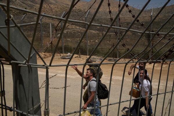 Syrian Druze people cross back into Syria as they walk at the Israeli-Syrian border, in the Israeli-controlled Golan Heights town of Majdal Shams, Thursday, July 17, 2025. (AP Photo/Leo Correa)