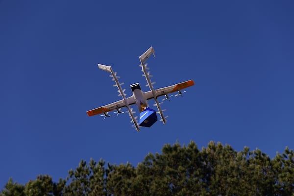 A Wing delivery drone carries a package through the air after taking off from Walmart Supercenter in Woodstock on Wednesday, Dec. 3, 2025. The drone-delivery system can carry packages up to two pounds, dropping them at a designated landing zone at a customer’s home. (Natrice Miller/AJC)