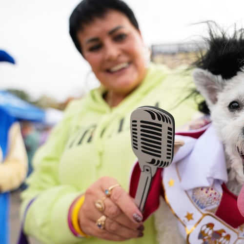 Michelle Dixon, of Laingsburg, holds her dog Abu, who is dressed as singer Elvis Presley, during an event for dog trick-or-treating, Friday, Oct. 17, 2025, in Lansing, Mich. (AP Photo/Ryan Sun)