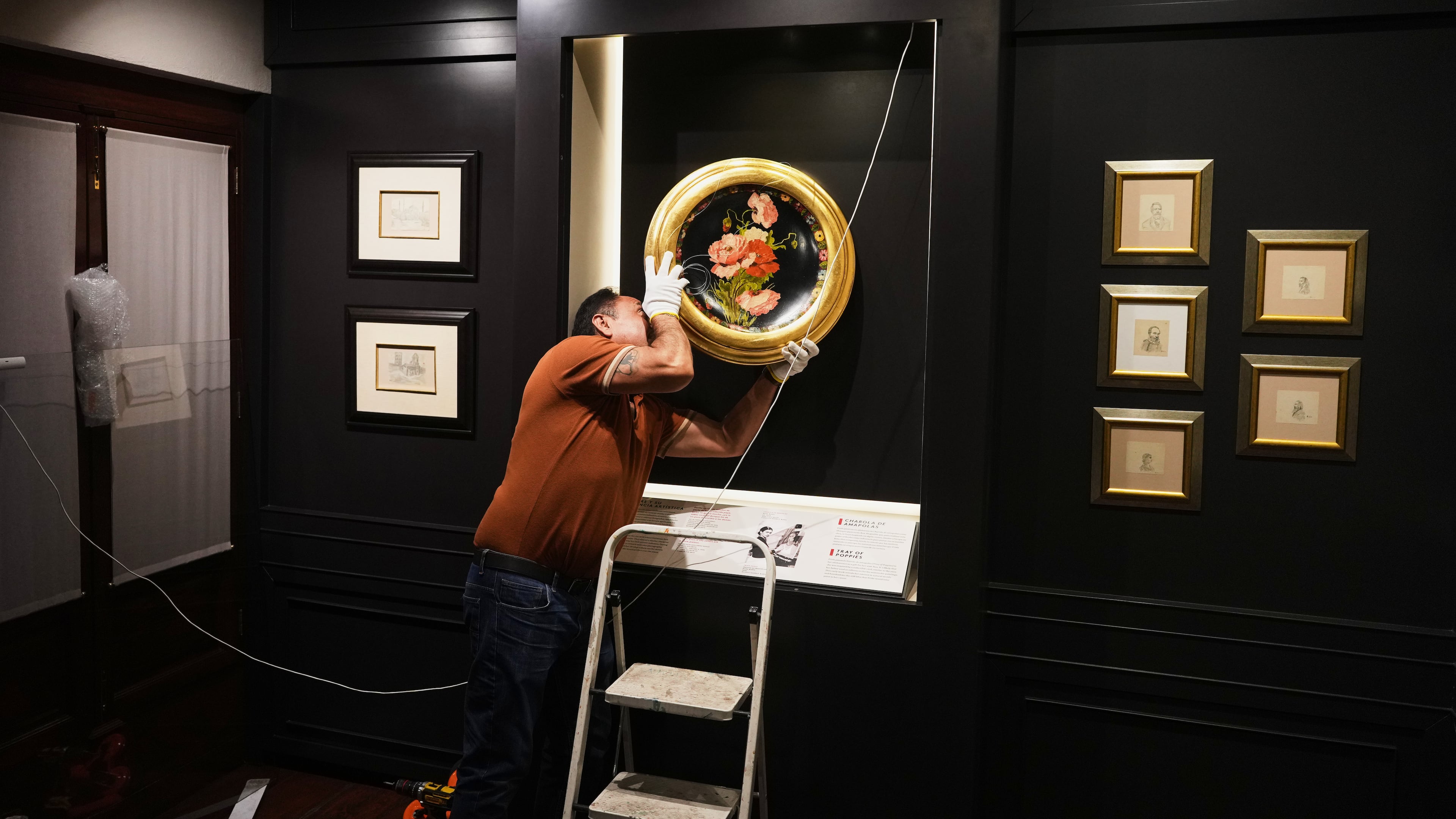 A curator hangs “A Tray of Poppies”, one of Frida Kahlo’s first works that she painted as gift for her Aunt Ana, in preparation for the opening of the new museum Casa Kahlo, a house bought by Kahlo’s father after he gave the iconic Casa Azul to his daughter as a wedding gift, in Mexico City, Wednesday, Sept. 10, 2025. (AP Photo/Eduardo Verdugo)